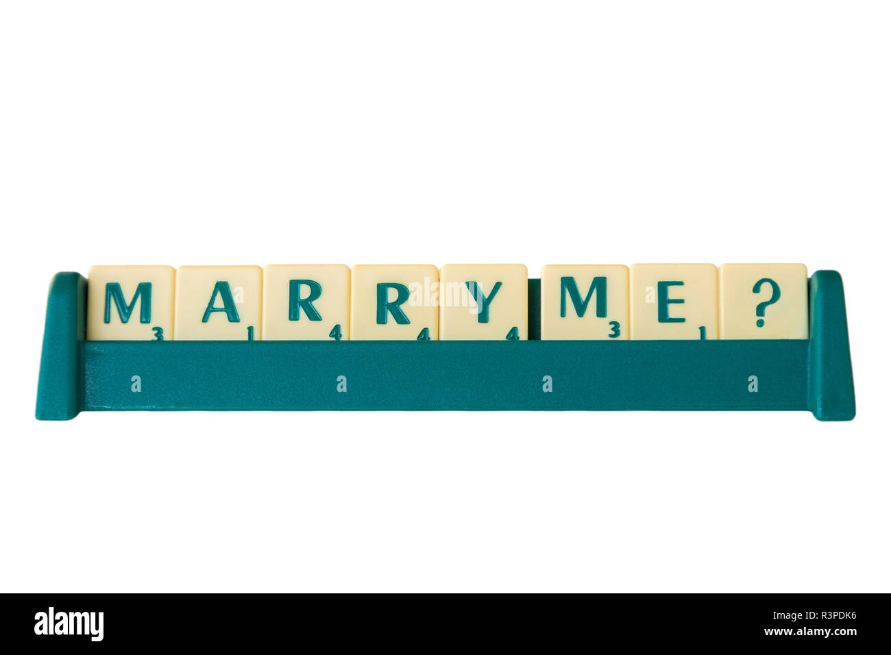 Scrabble game letter tiles with score value on a stand forming the phrase 'Marry Me?'. Isolated on white background. Stock Photo