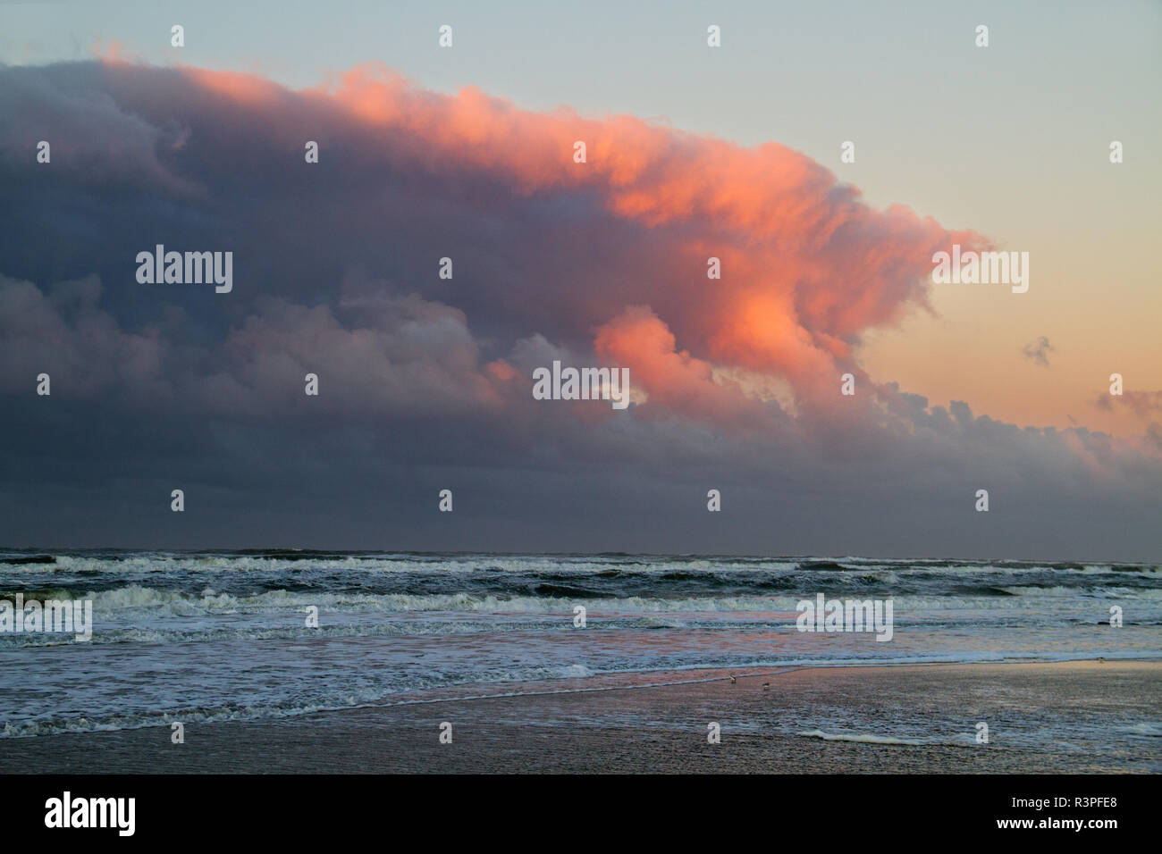 Storm front approaching over the sea after sunset: threatening red clouds above the dark water Stock Photo