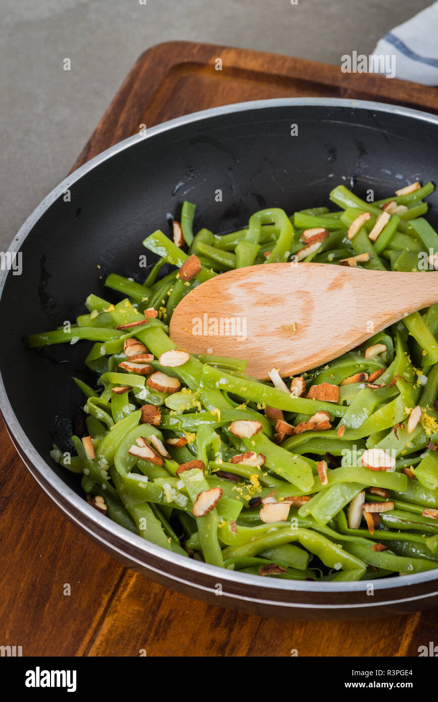Green beans with roasted almonds on fry pan on kitchen countertop Stock