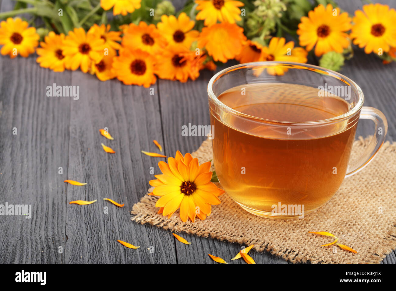 Calendula tea with fresh flowers on black wooden background Stock Photo