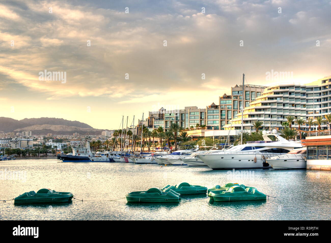 small turquoise pedalos in contrast to large yachts in the marina of Eilat Stock Photo