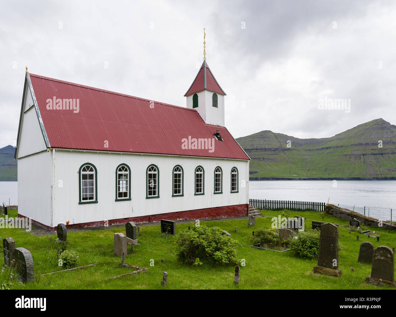 The island of Kunoy with village Kunoy and church. In the background island Kalsoy. Faroe Islands, Denmark Stock Photo