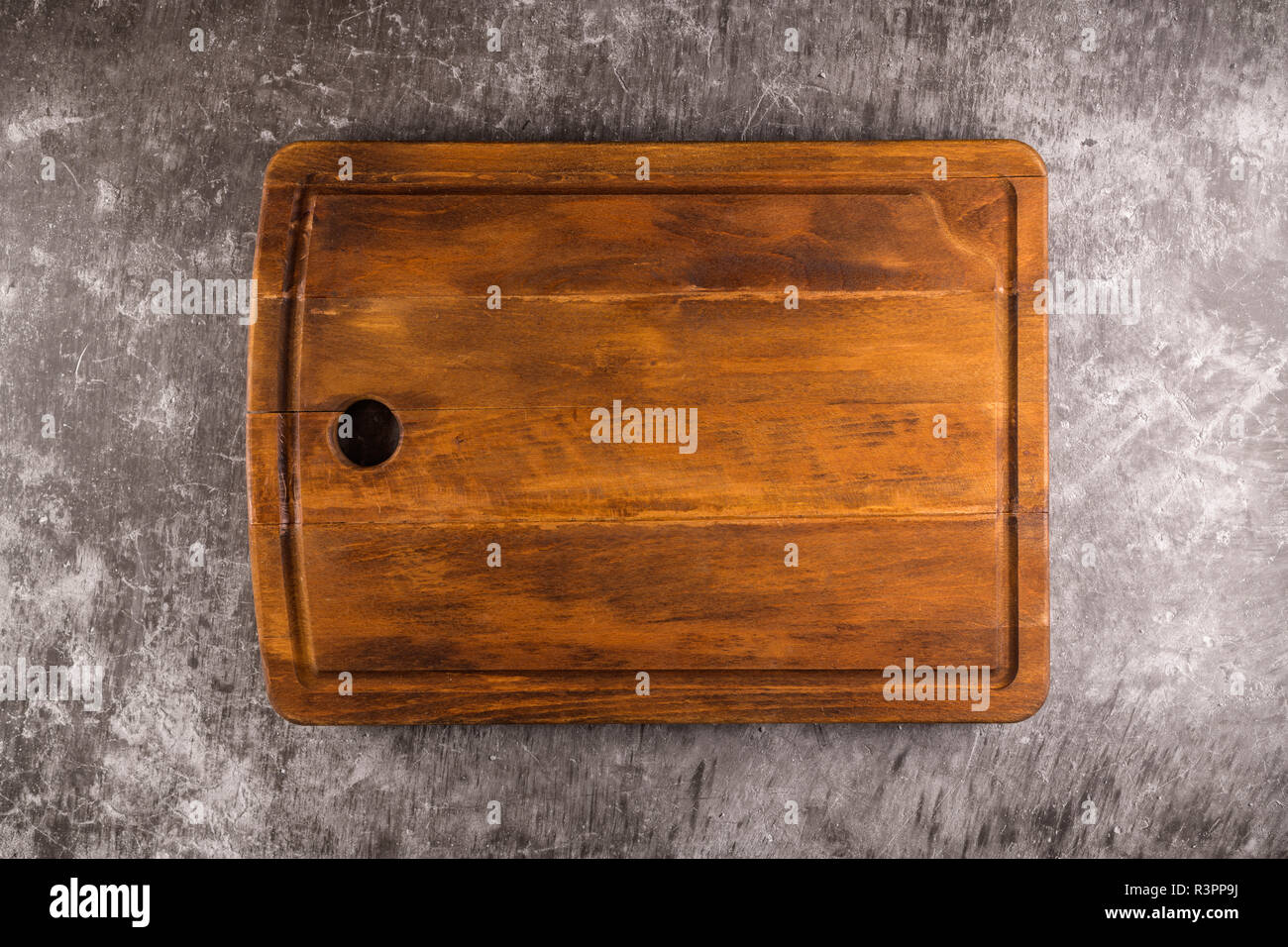 Top View Of Wooden Cutting Board On Old Stone Countertop Stock