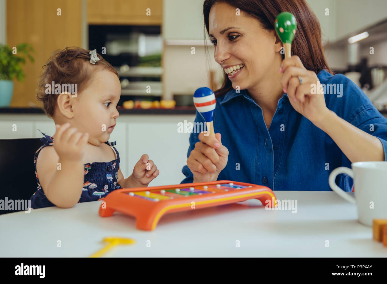Happy mother and baby daughter playing with rattles Stock Photo