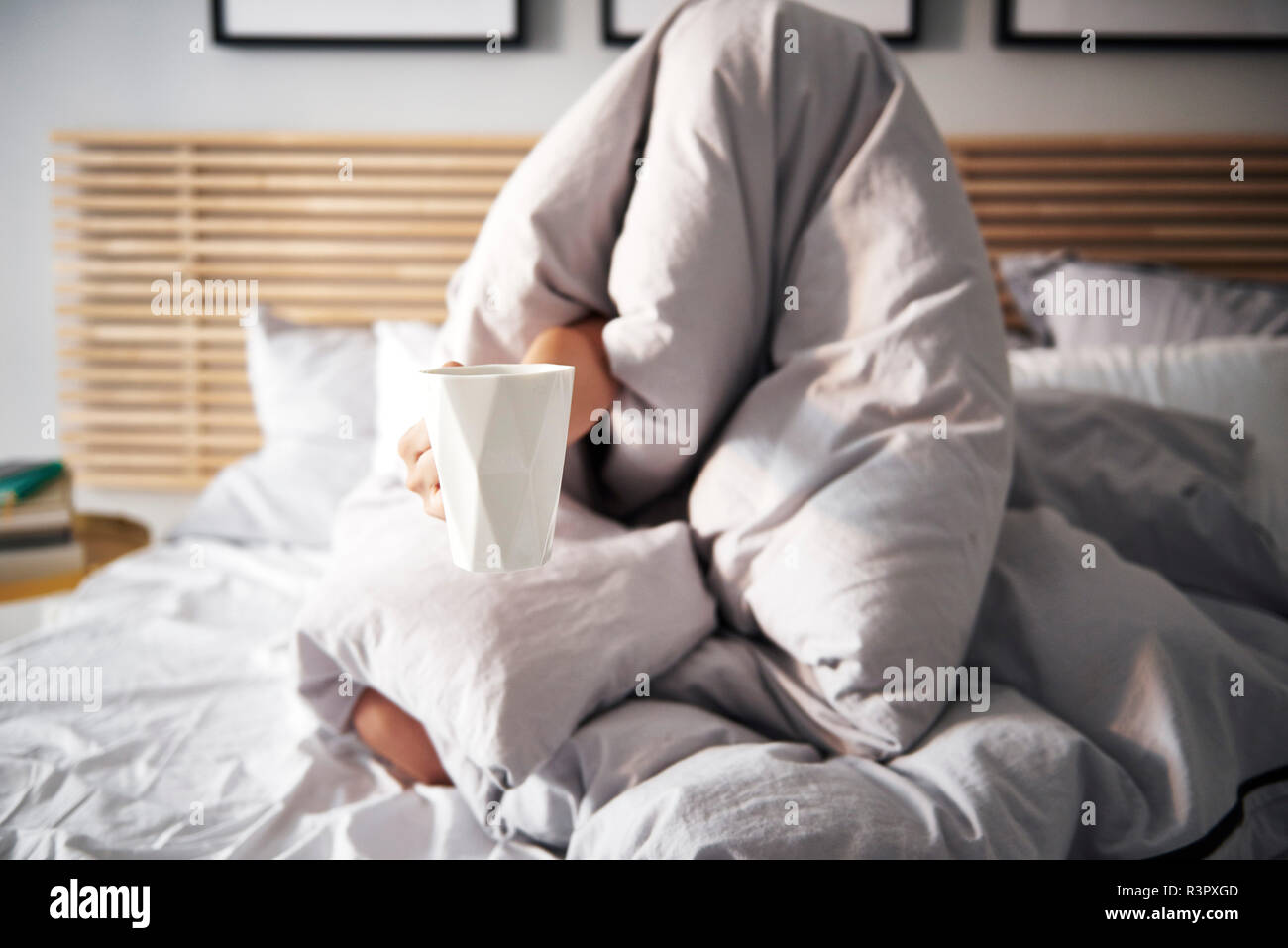 Woman hidden under blanket demanding coffee Stock Photo