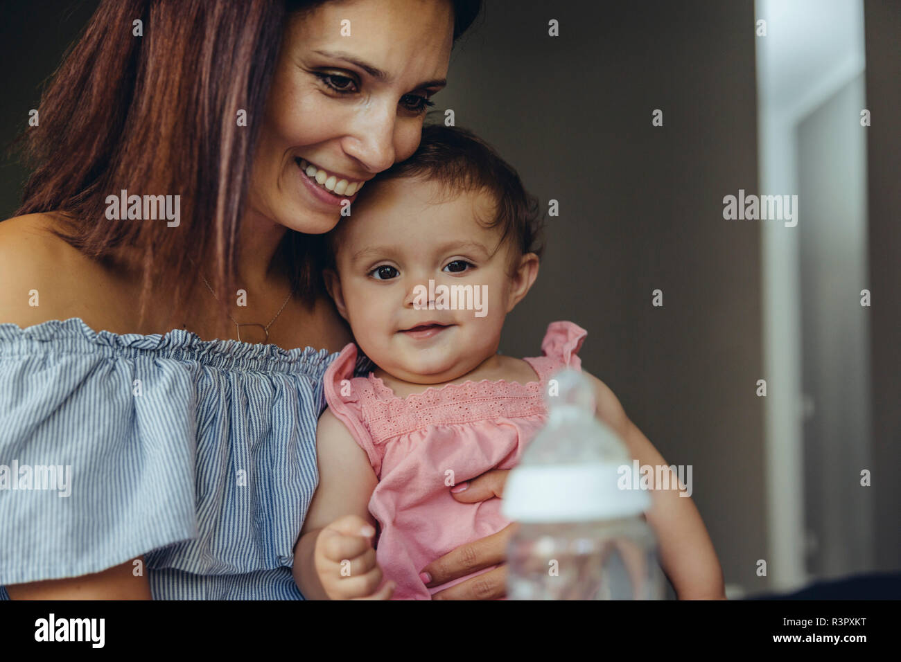 Mother offering her baby girl milk in a bottle Stock Photo