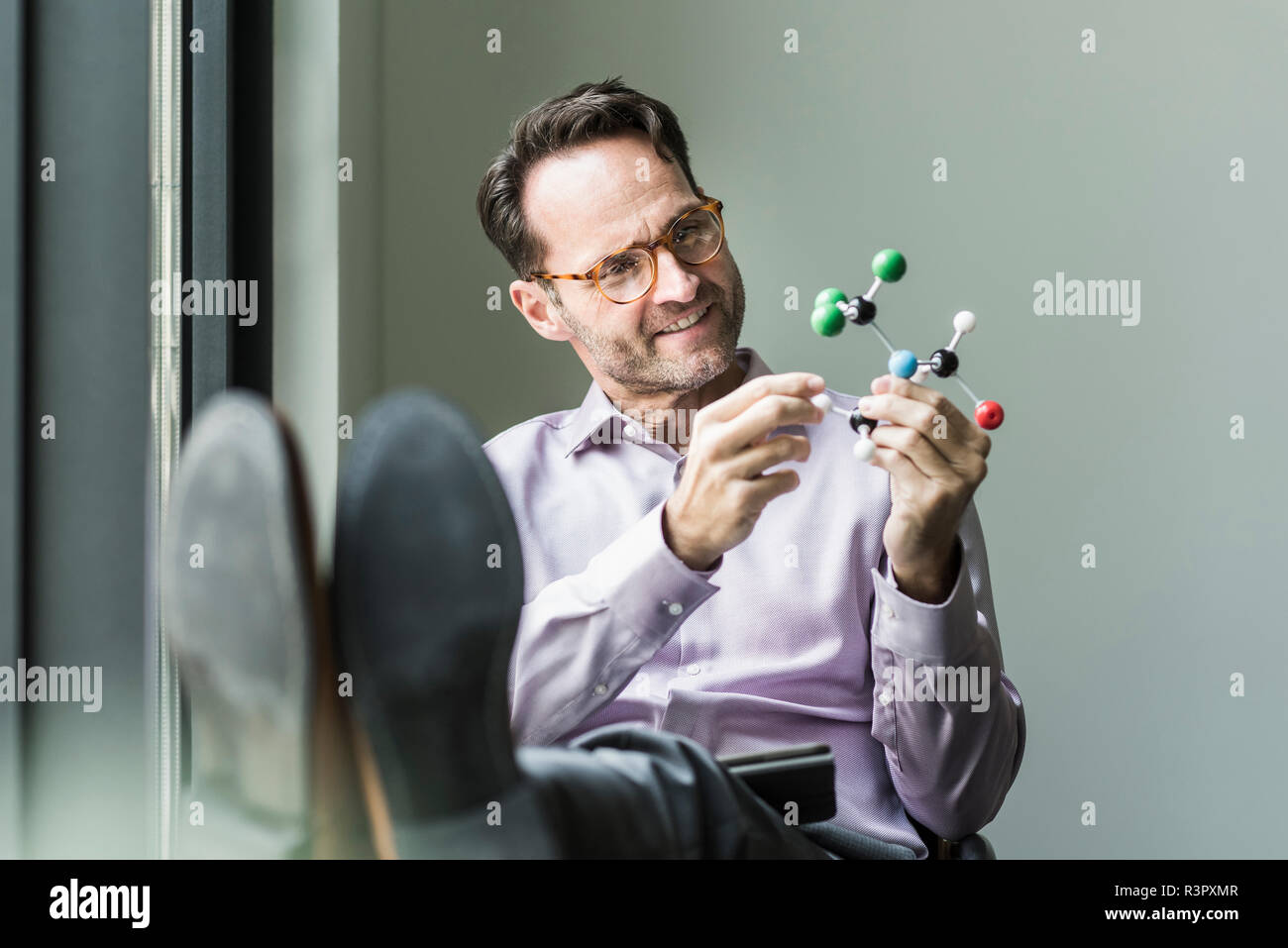 Portrait of smiling man with atomic model Stock Photo