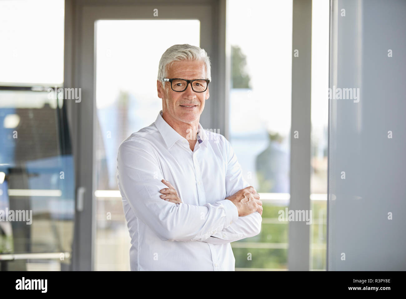 Confident businessman standing in office, with arms crossed Stock Photo