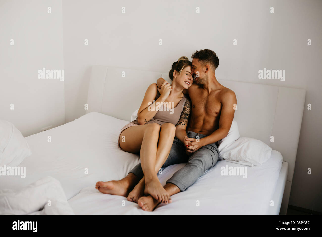 Happy young couple sitting in bed Stock Photo