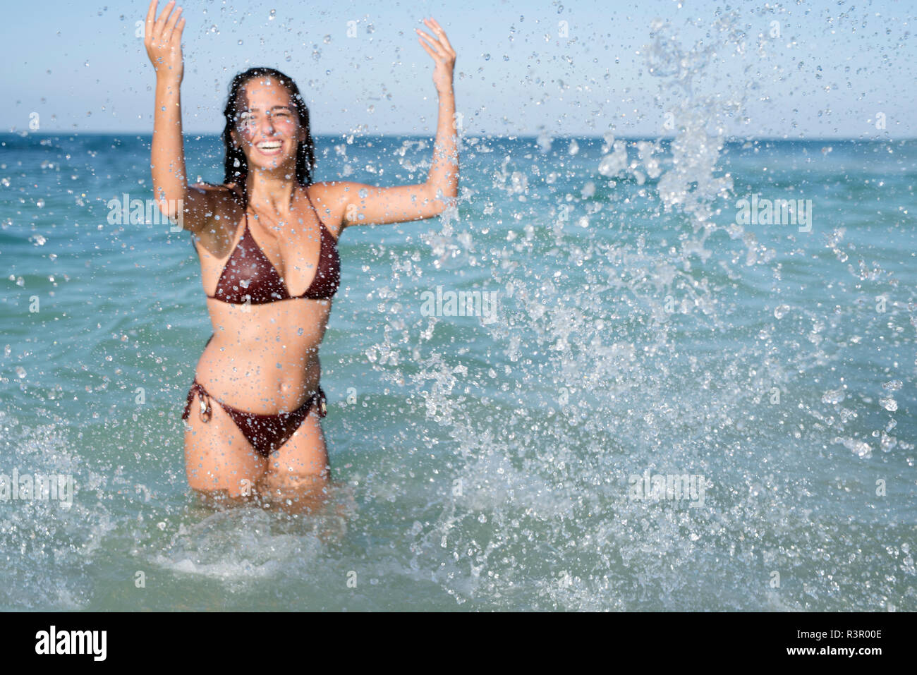 Happy carefree young woman splashing in the sea Stock Photo