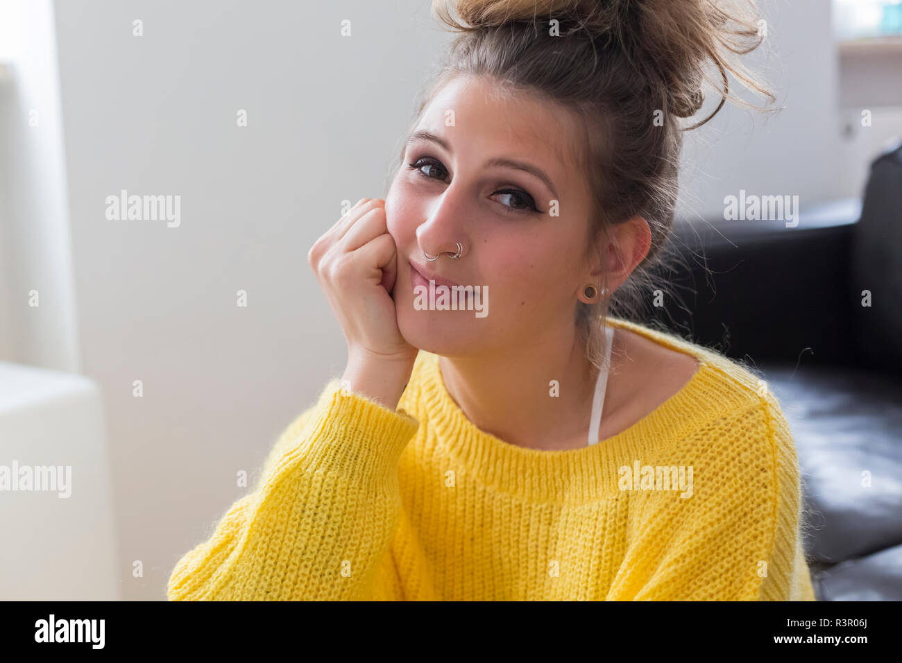 Portrait of smiling young woman with nose piercing wearing yellow pullover Stock Photo