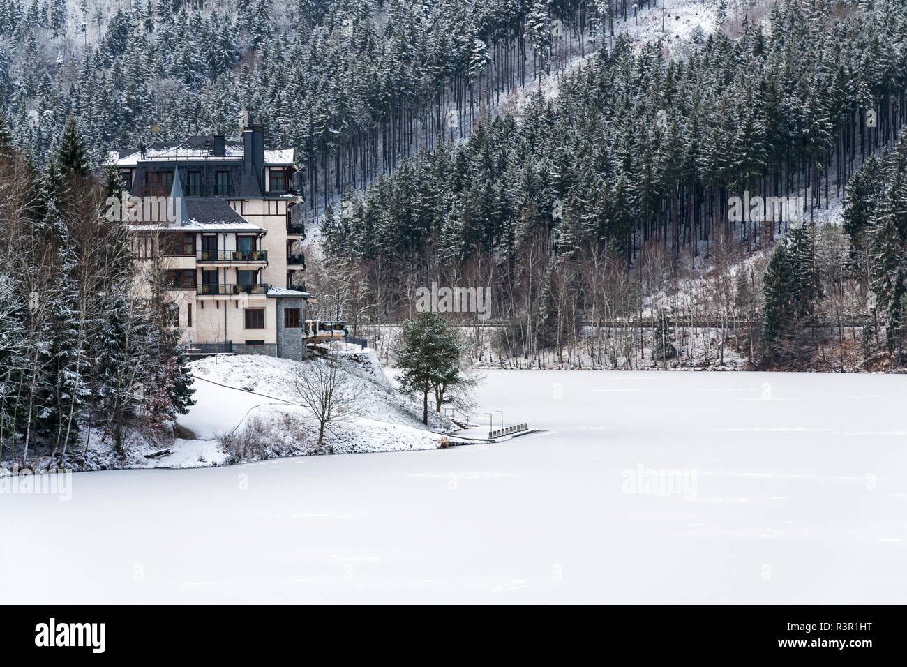 Solitary hotel building in a beautiful snowy winter landscape with forest and frozen Brezova dam Stock Photo