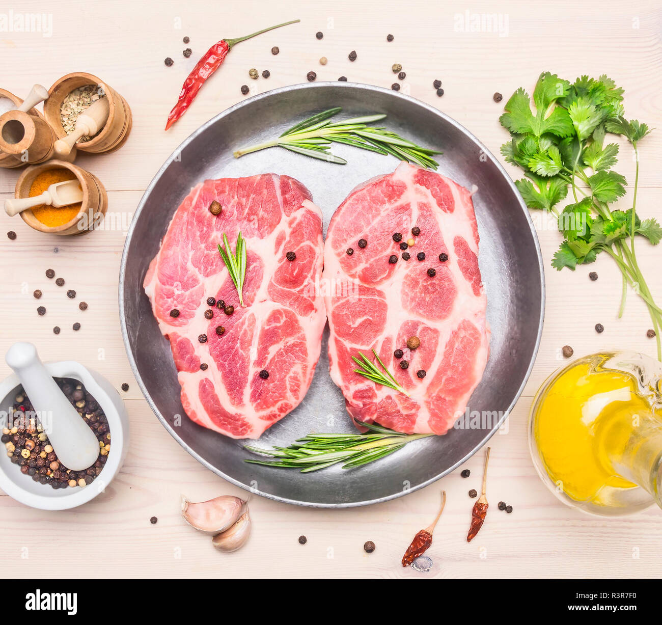 Two juicy raw pork steaks with rosemary and other seasonings, laid out