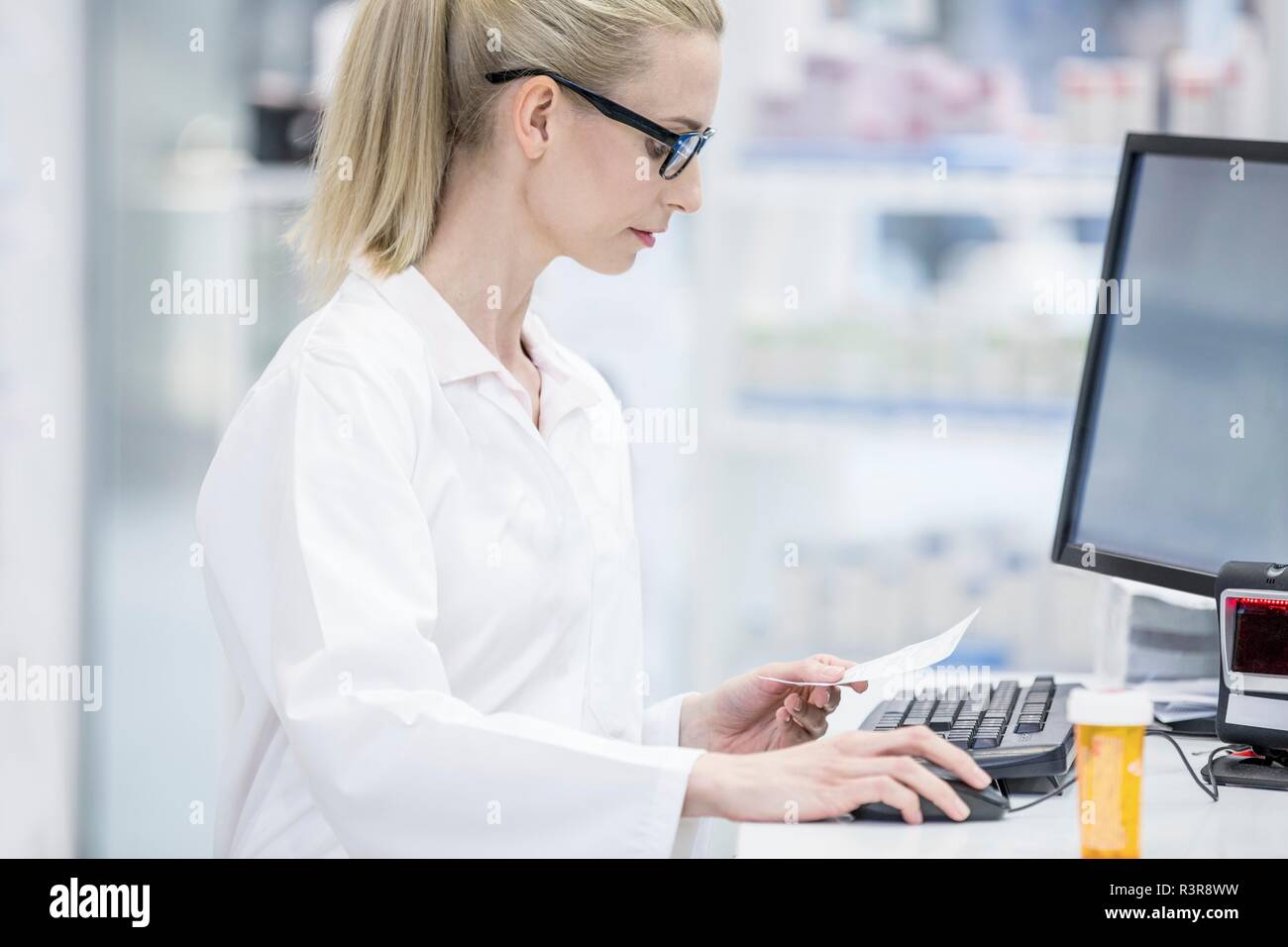 Female pharmacist working on computer in pharmacy. Stock Photo
