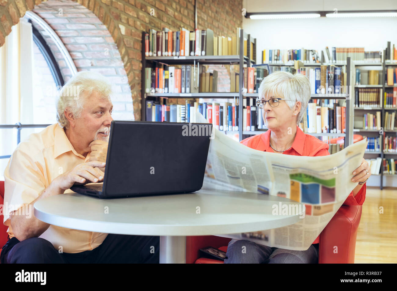 Ein Seniorenpaar sitzen in einer Bücherei und kommunizieren über digitale Medien.  Grevenbroich, Nordrhein-Westfalen, Deutschland Stock Photo