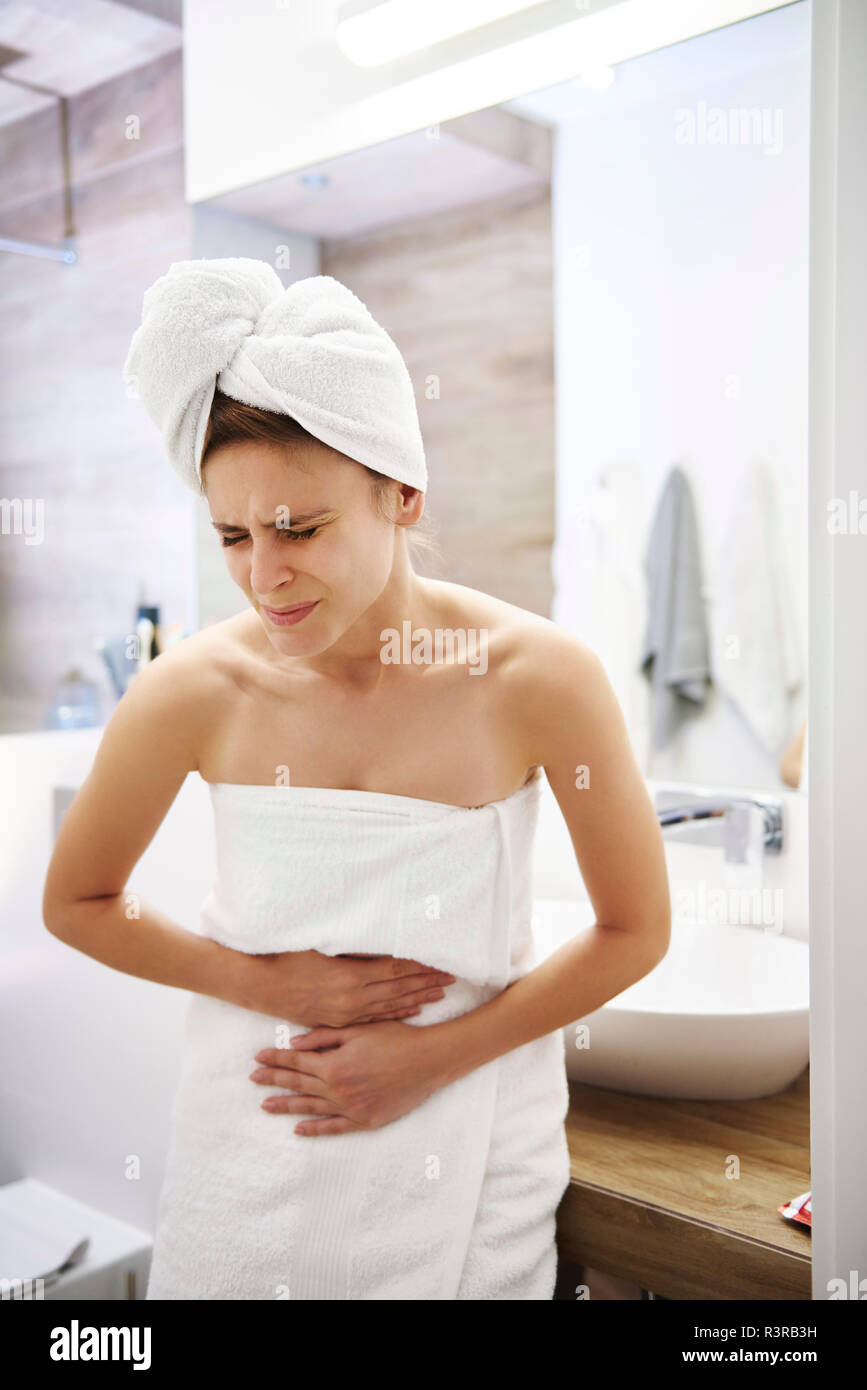 Young woman in bathroom suffering from stomach pain Stock Photo