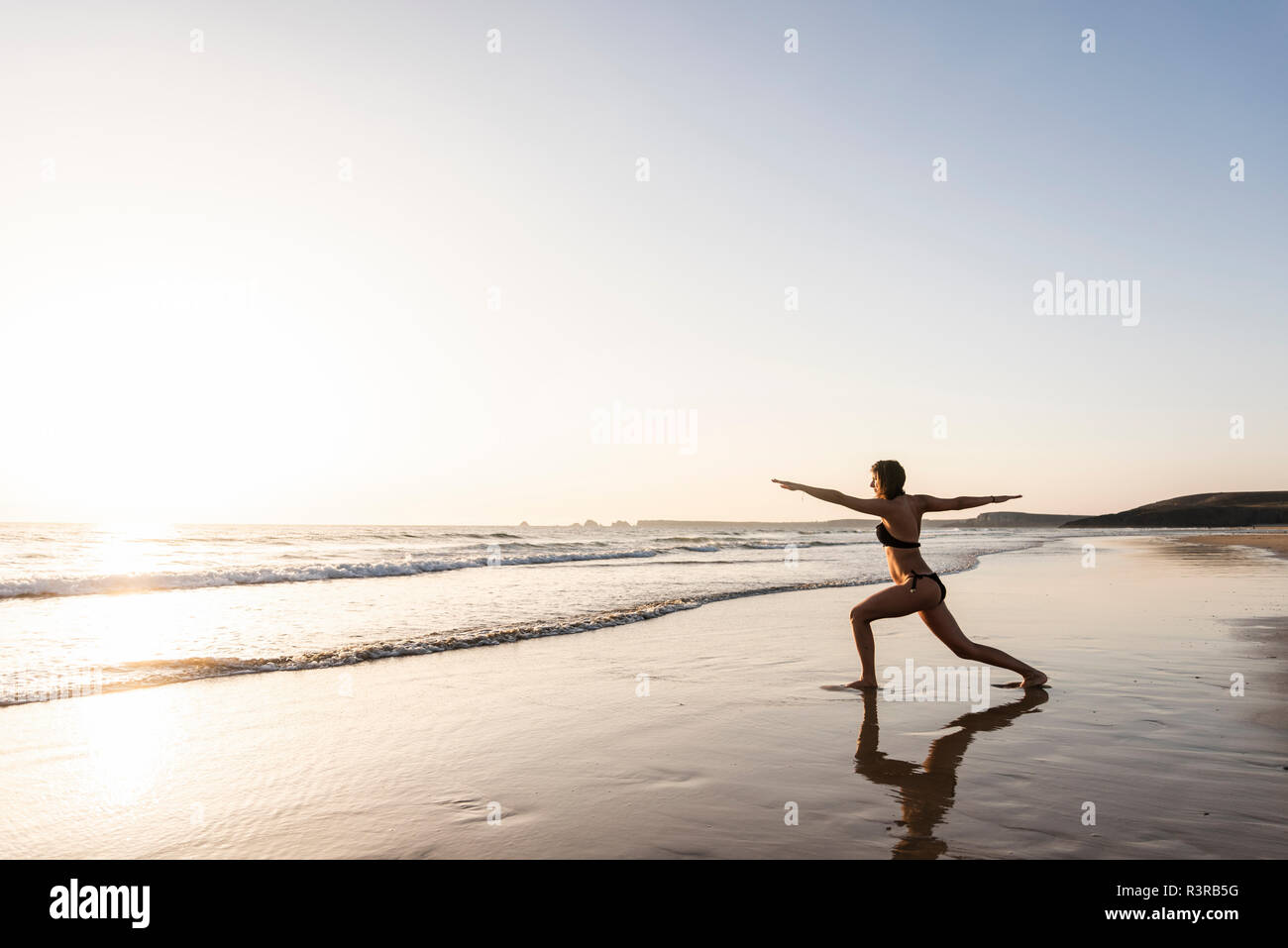 Young woman practicing yoga on the beach Stock Photo