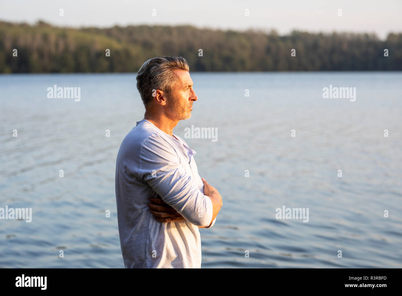 Pensive man standing at lake looking at distance Stock Photo