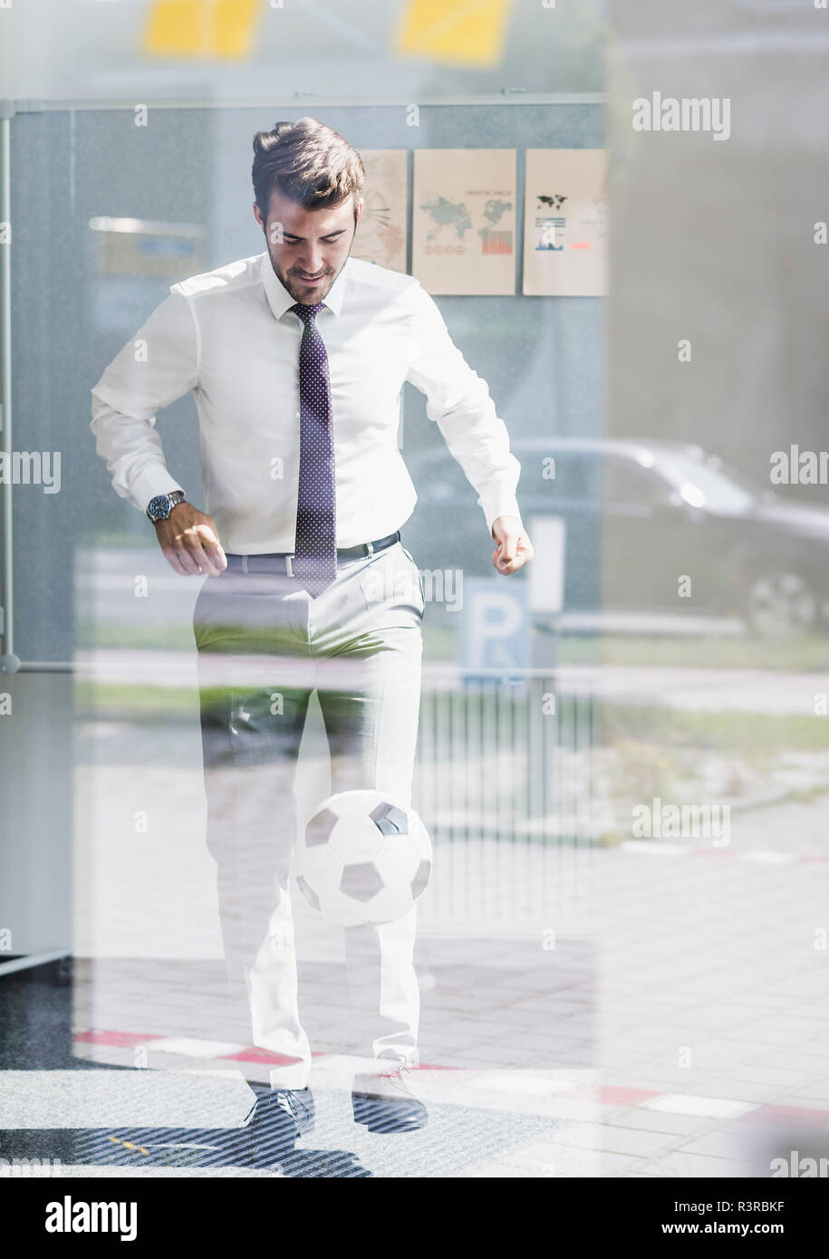 Businessman playing football in office Stock Photo