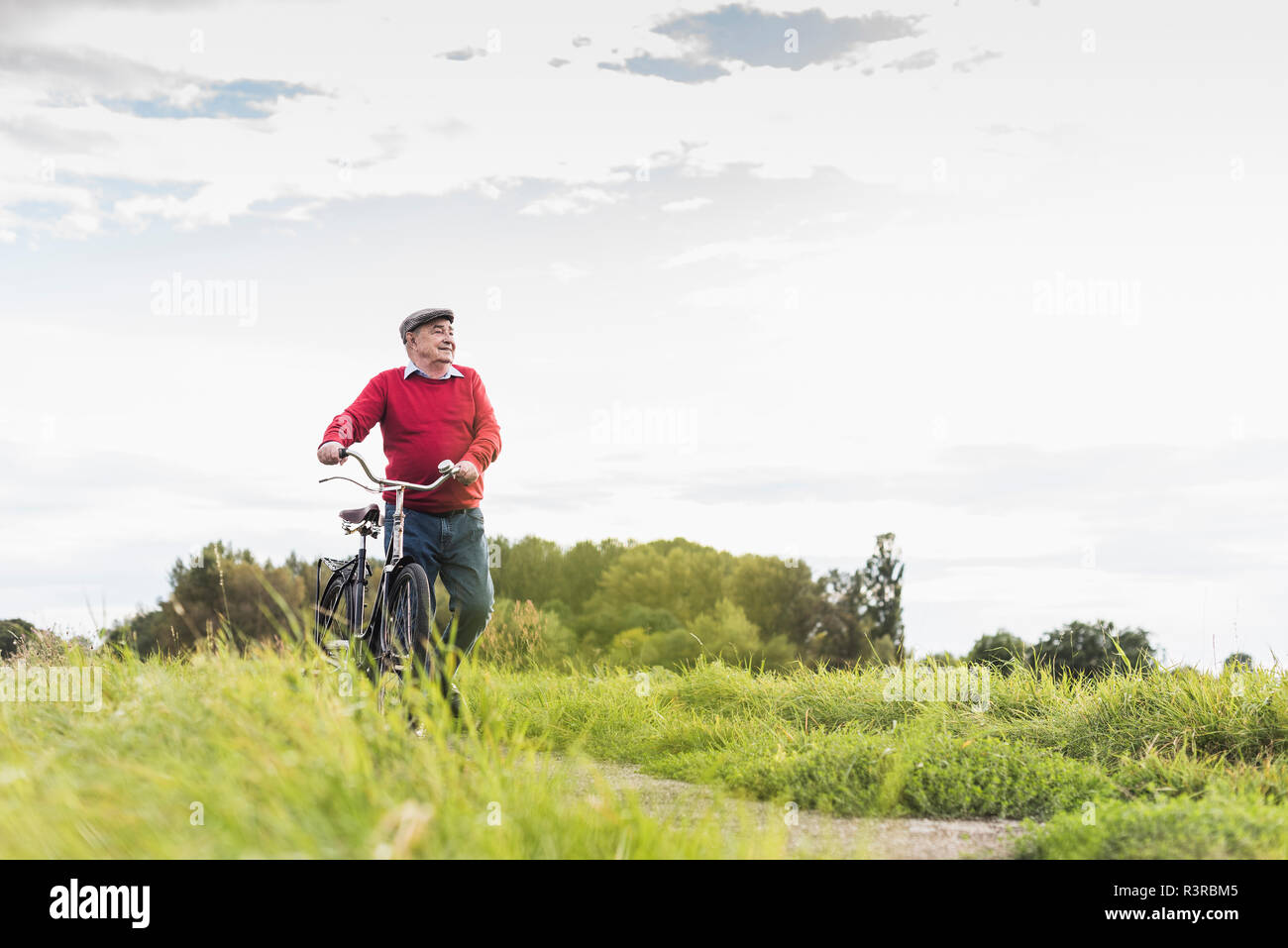 Senior man pushing bicycle in rural landscape Stock Photo