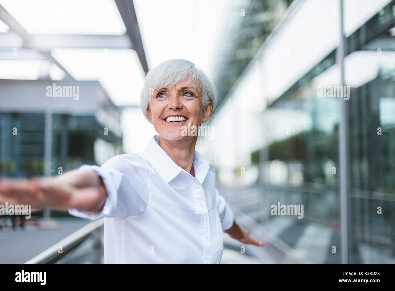 Happy senior woman in the city with outstretched arms Stock Photo