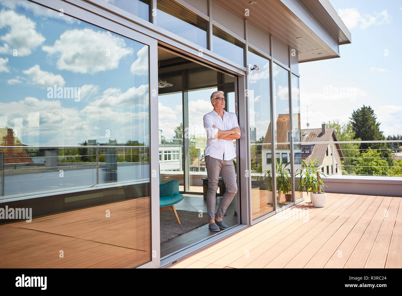 Mature man relaxing standing at roof terrace at home Stock Photo