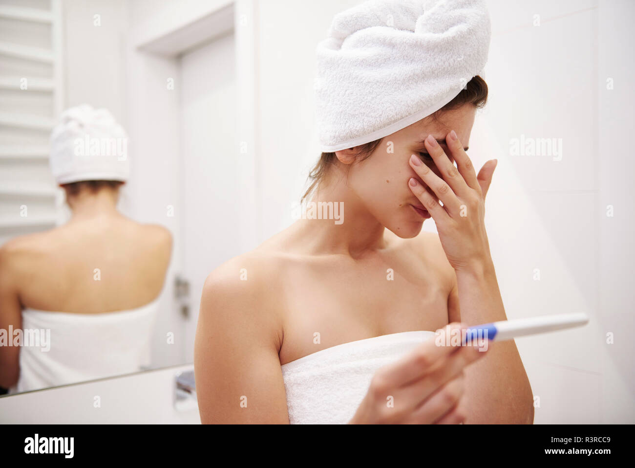 Young woman in bathroom worrying over pregnancy test result Stock Photo