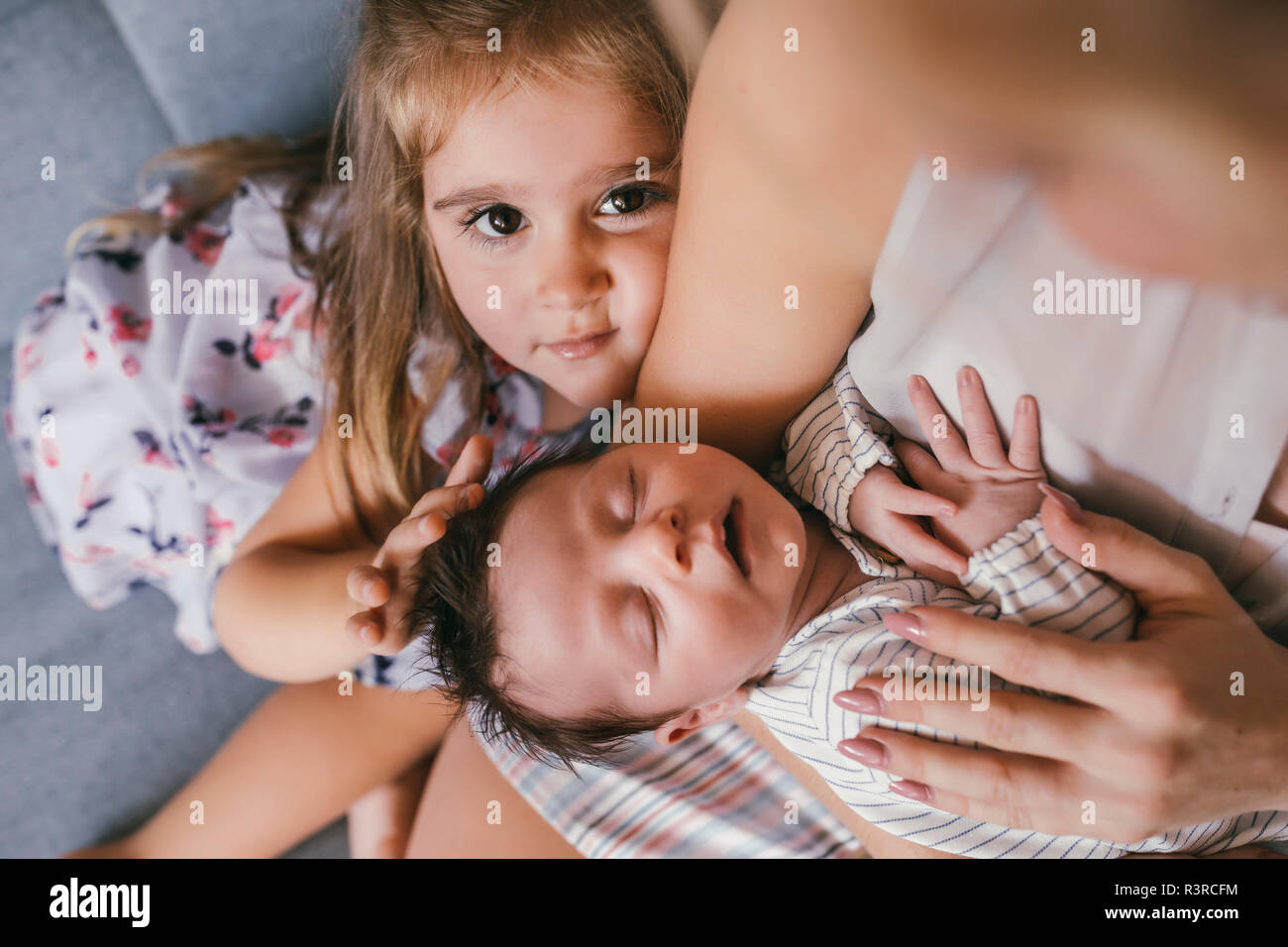 Mother holding her baby close with sister feeling his hair Stock Photo