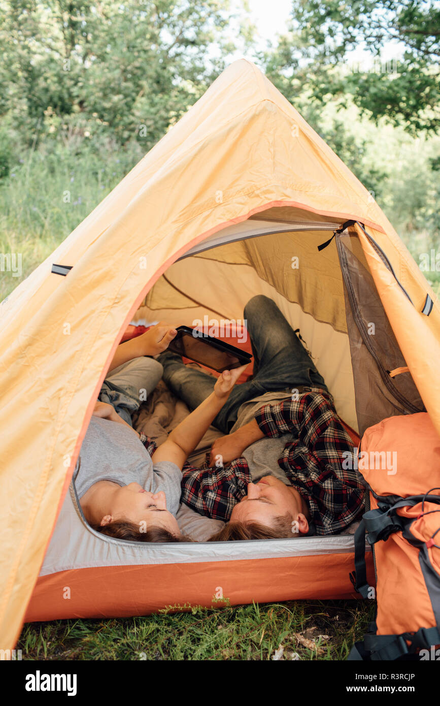 Young couple relaxing in tent, using digital tablet Stock Photo