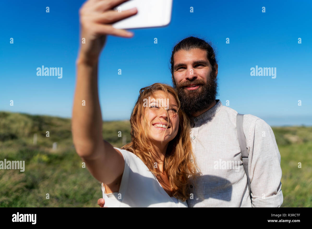 Young couple taking smartphone selfies on the beach Stock Photo