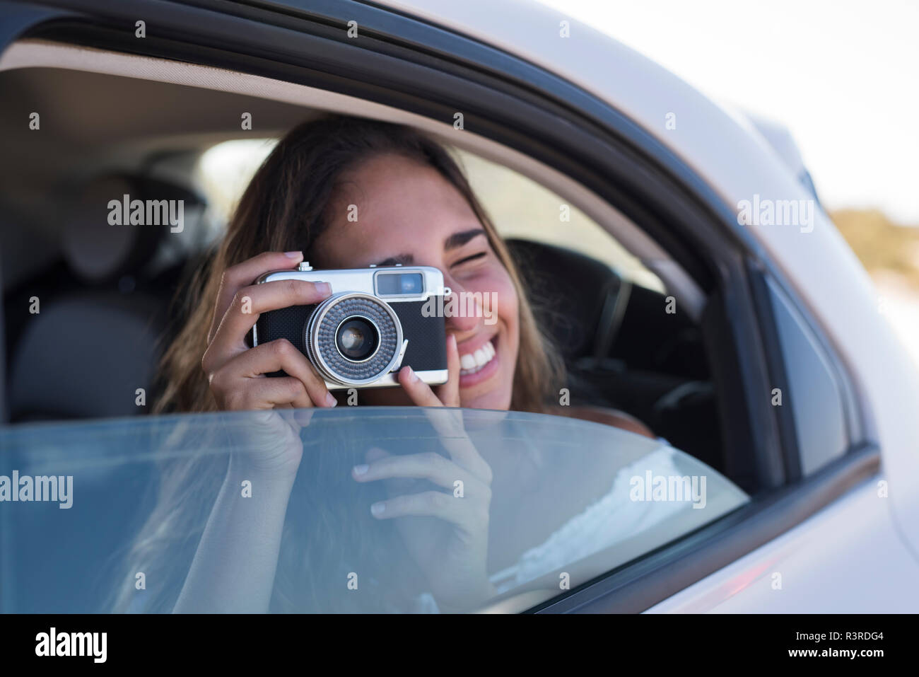 Woman sitting in car, taking pictures with a camera Stock Photo
