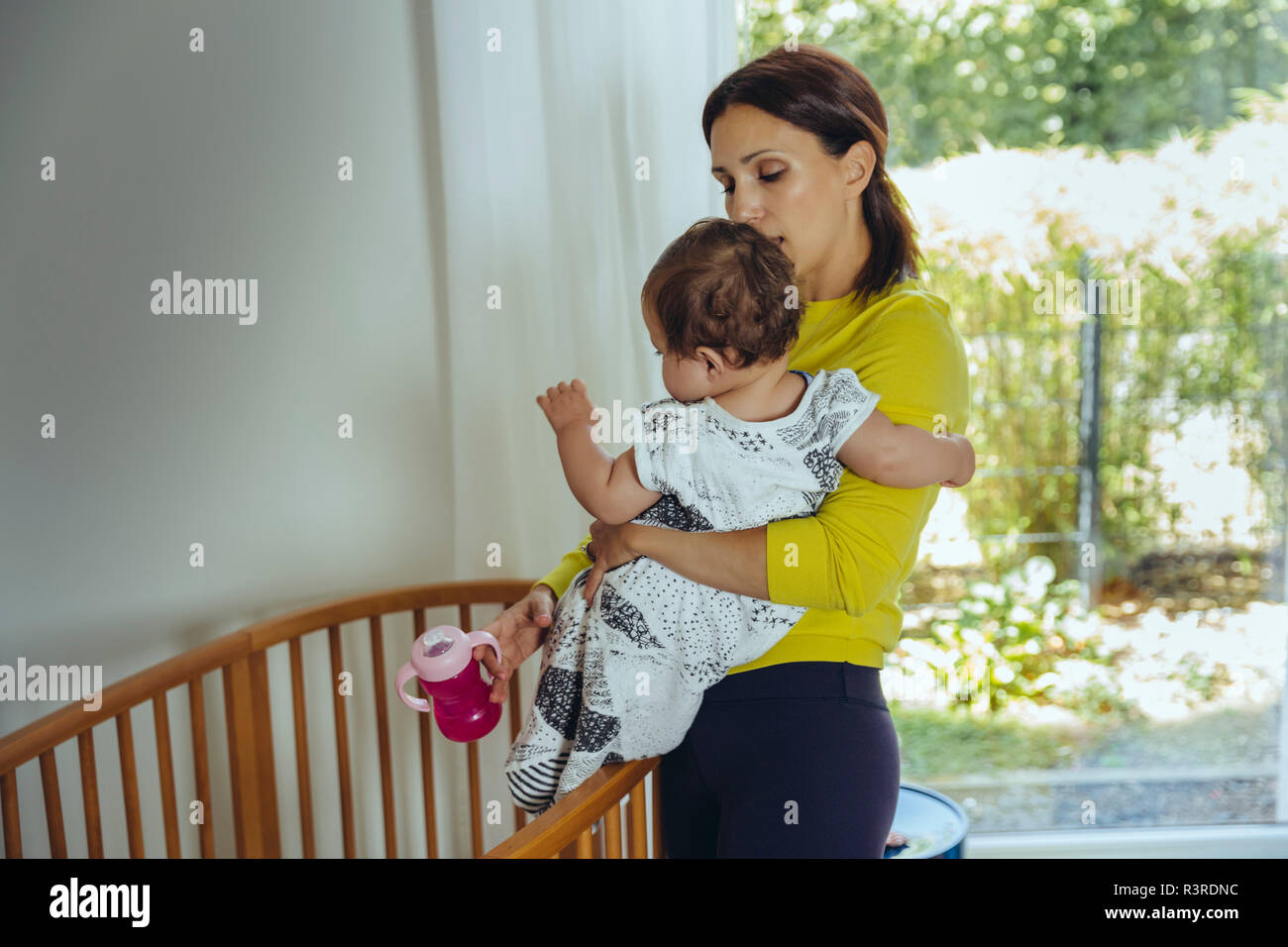 Mother putting her baby girl to bed Stock Photo Alamy