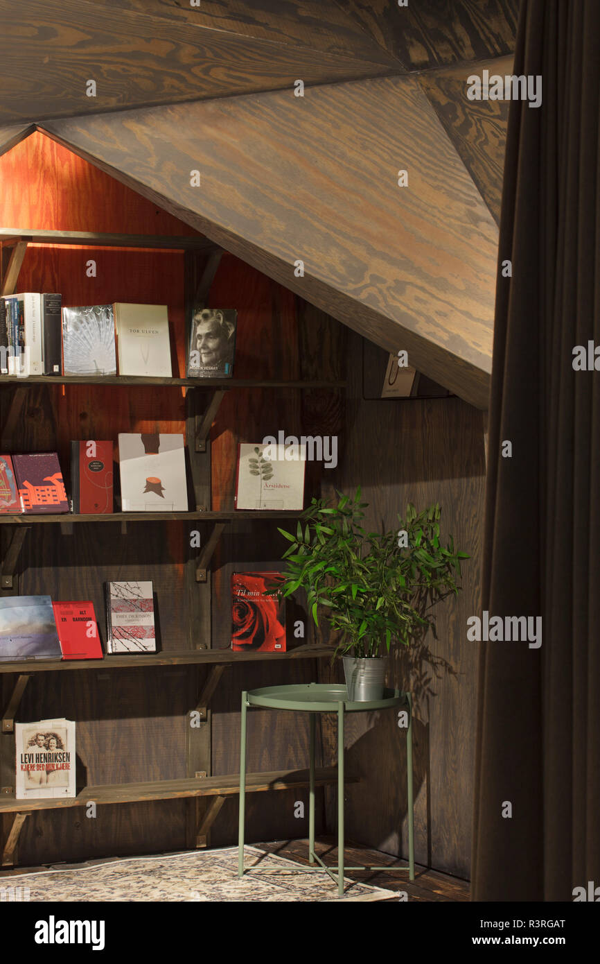 Geometric timber alcove with shelving against orange back wall ...