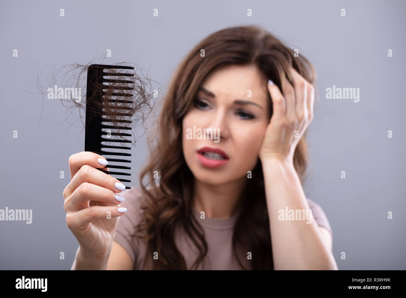 Close-up Of A Worried Woman Holding Comb Suffering From Hairloss Stock Photo