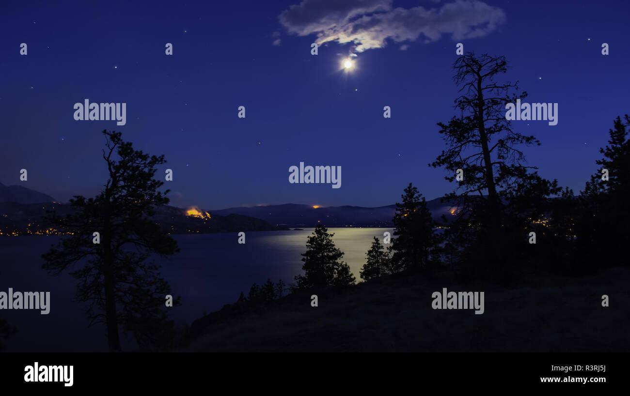 Night view of Okanagan Lake near Peachland and Kelowna British Columbia Canada in the moon light with many forest fires burning in the background Stock Photo
