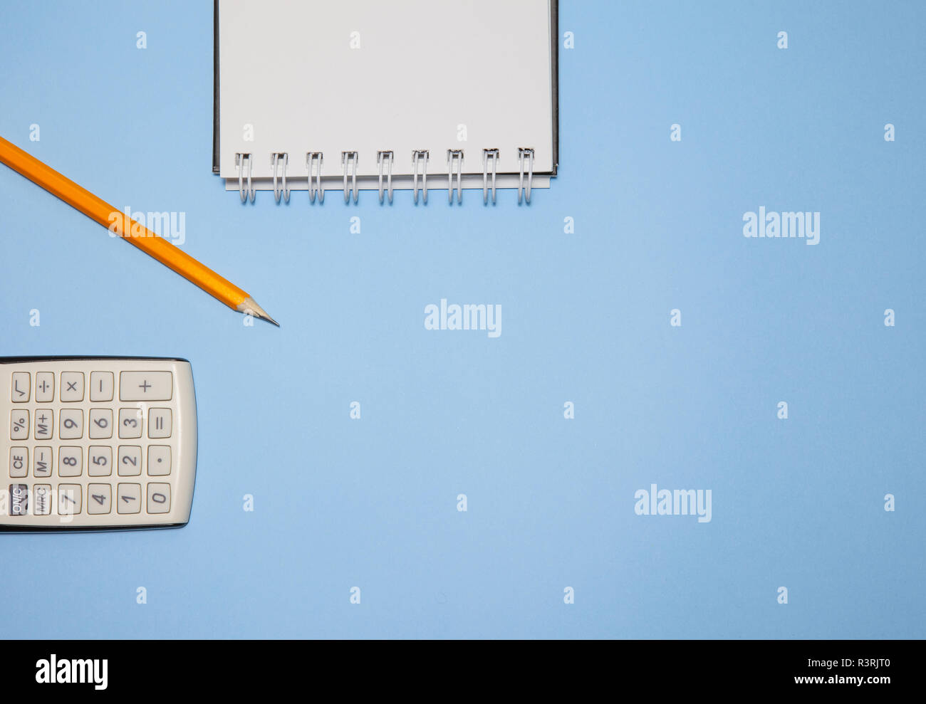 Notepad, calculator and pencil on blue background, top view Stock Photo