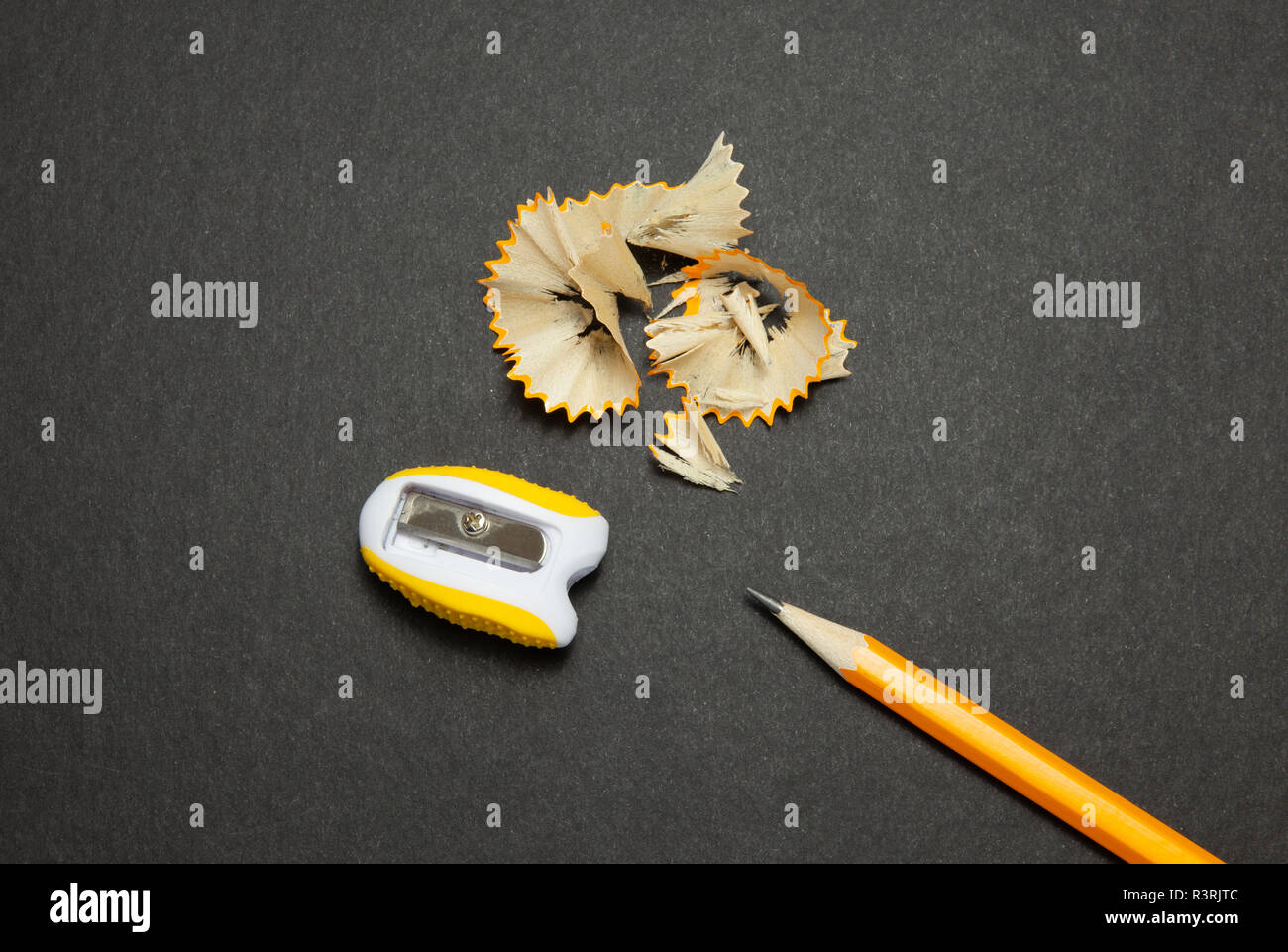 Sharpened pencil and sharpener on black background, top view Stock Photo