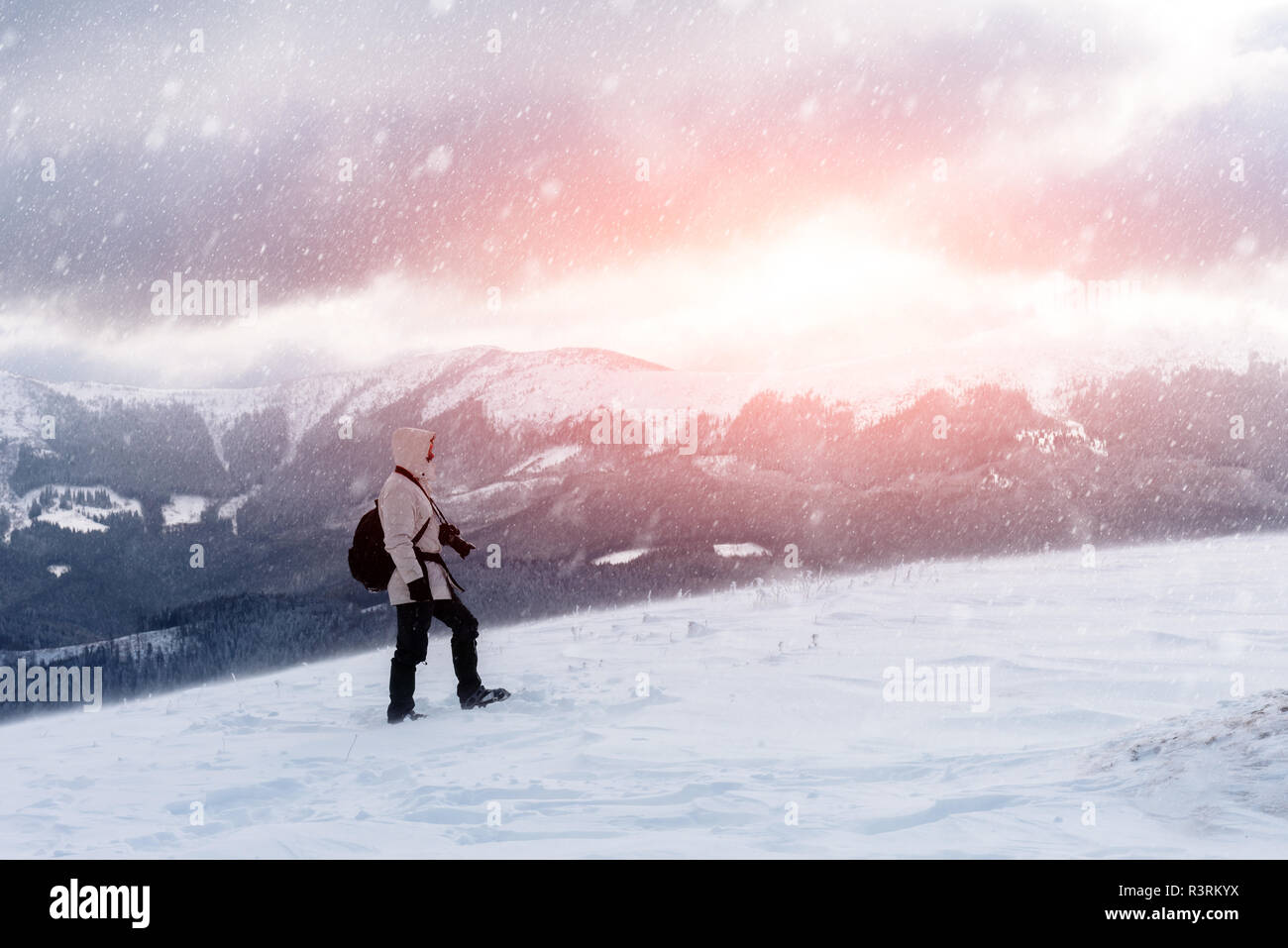 Alone photographer on mountain top in snowstorm with a backpack in winter time. Travel concept. Carpathian mountains. Landscape photography Stock Photo