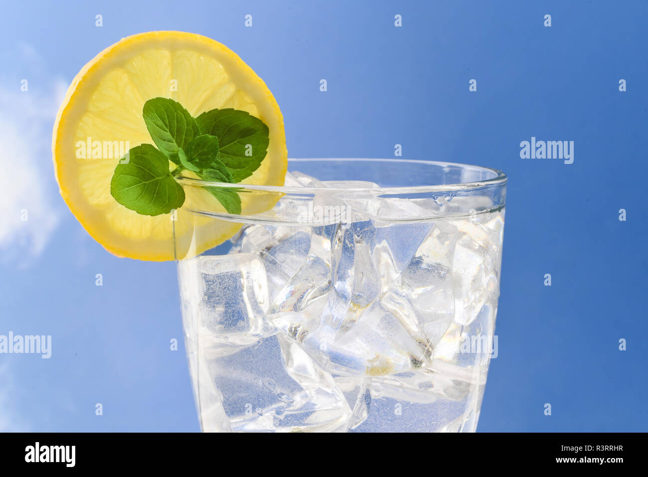 top of a glass with fresh water, ice cubes, lemon slice and mint ...
