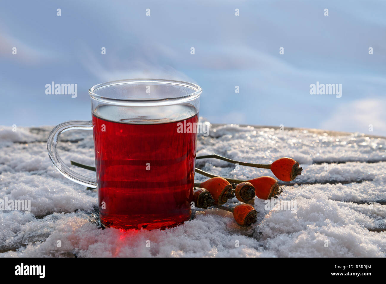 hot red tea from hibiscus and rose hip fruits outdoors in the winter snow, healthy warming drink for immunity protection against cold and flu in the c Stock Photo