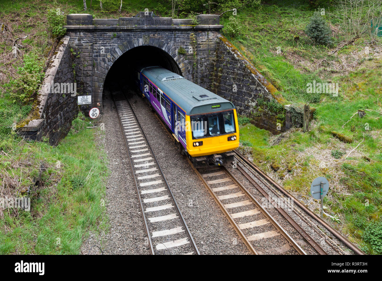 Countryside railway tunnel. A Northern Rail train emerging from Totley Tunnel as it approaches Grindleford Railway Station, Derbyshire, England, UK Stock Photo
