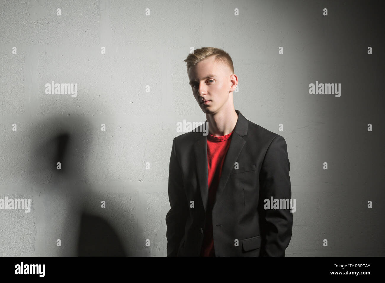 Portrait of serious young man wearing black suit coat and red t-shirt Stock Photo
