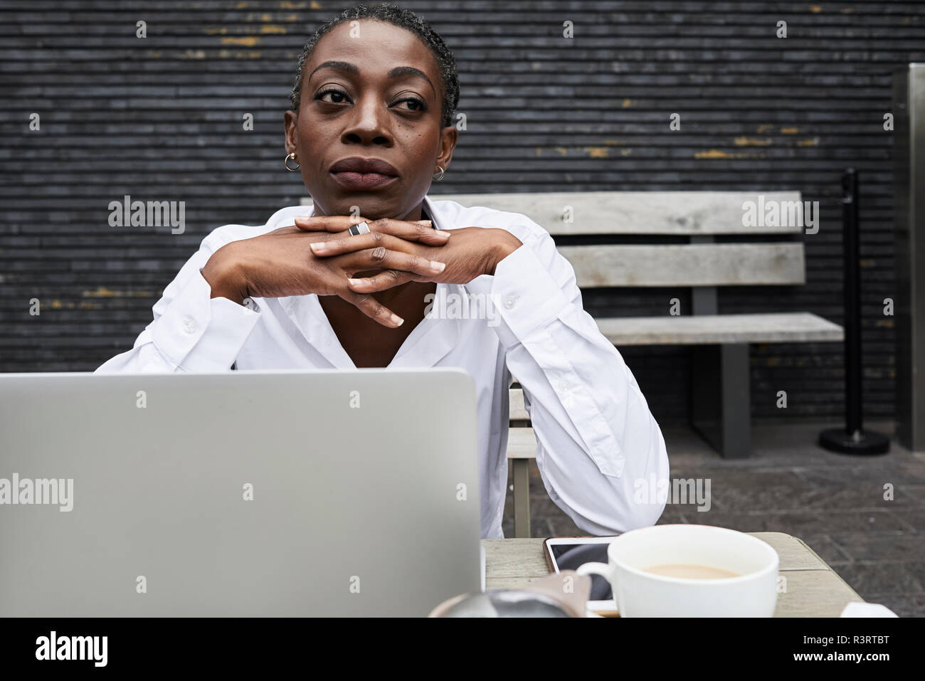 Portrait of pensive businesswoman sitting on terrace of a coffee shop Stock Photo