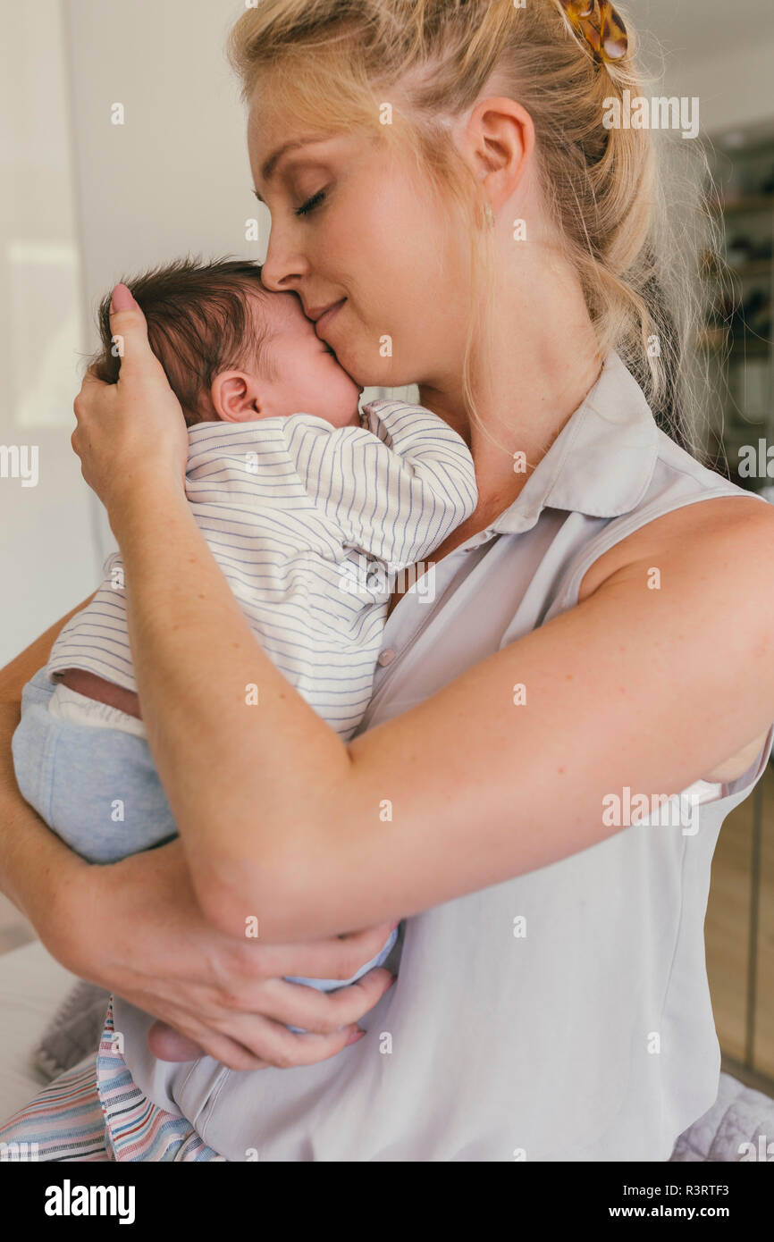 Happy mother holding her baby close to her shoulder Stock Photo