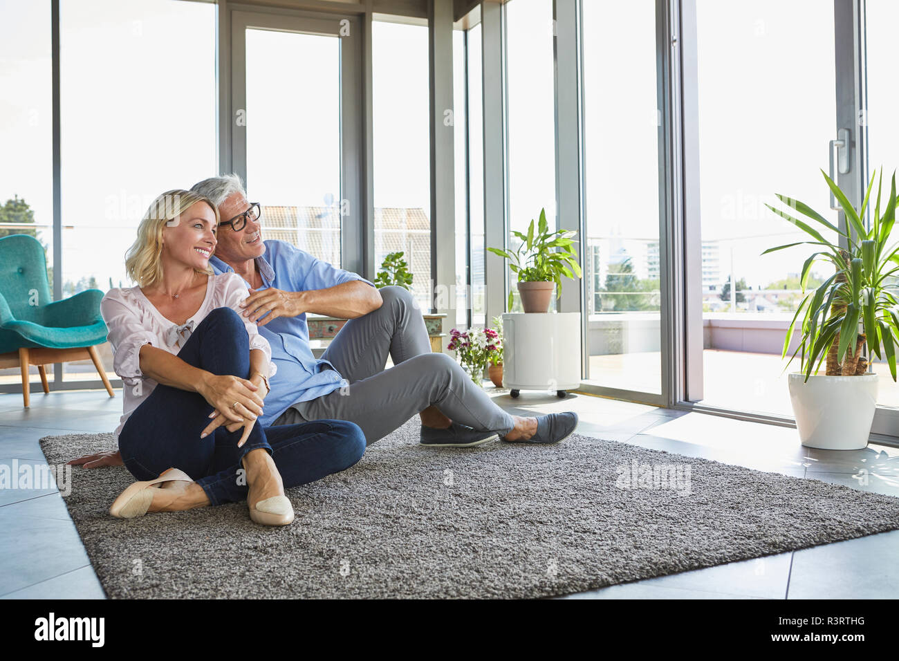 Smiling mature couple relaxing at home looking out of window Stock Photo