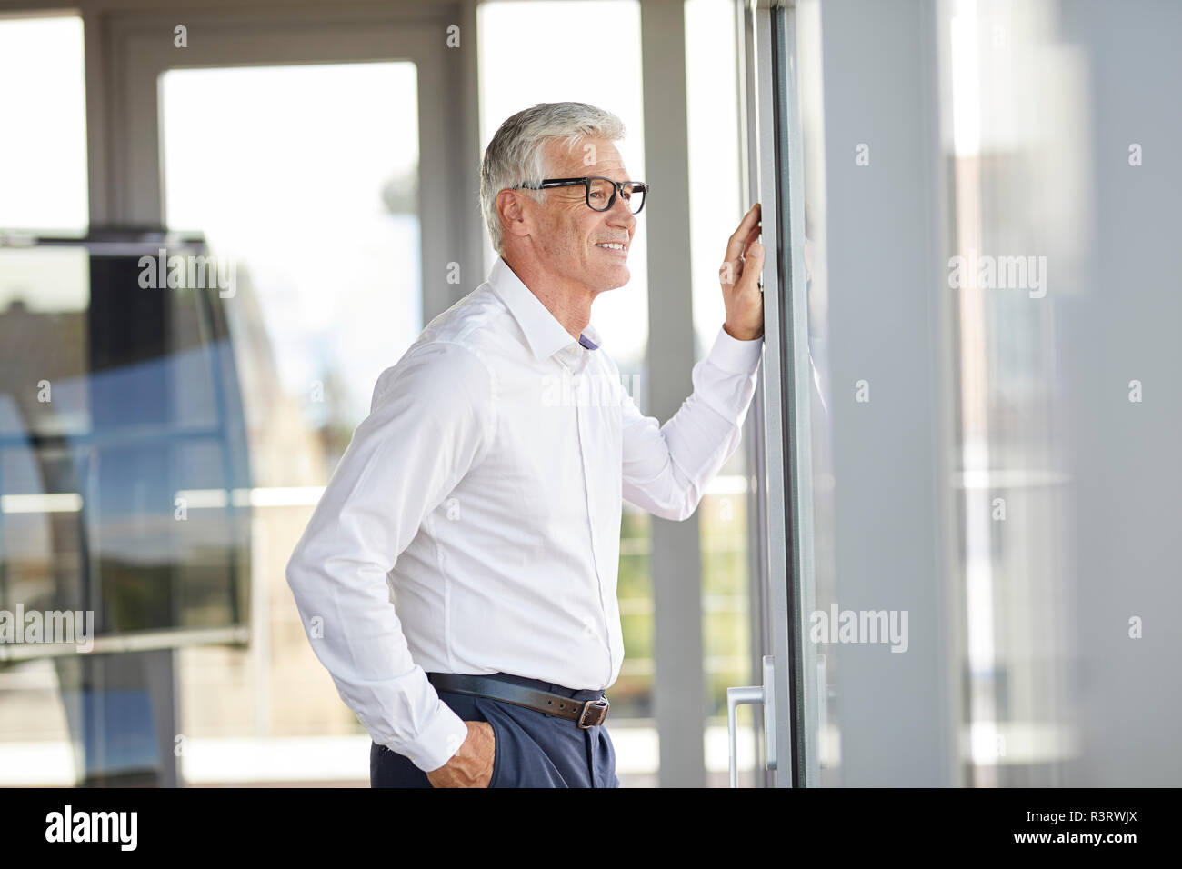 Confident businessman standing in office, looking out of window Stock Photo