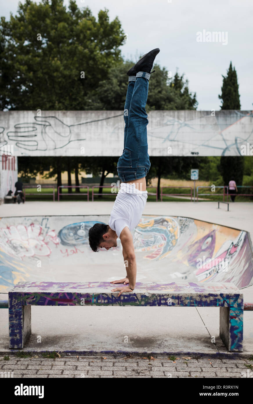 Young man doing a handstand on bench in skatepark Stock Photo