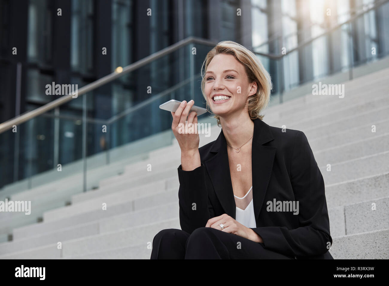 Portrait of smiling businesswoman  sitting on stairs outdoors talking on mobile phone Stock Photo