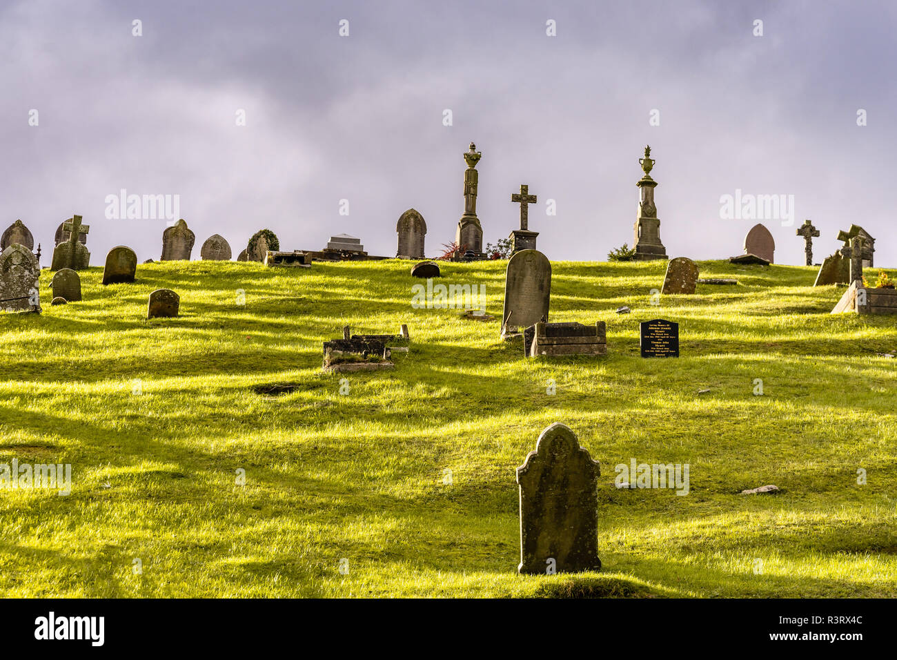 Sunlight and cloudy sky over old graves at Pant cemetery in Merthyr Tydfil, Wales, UK Stock Photo