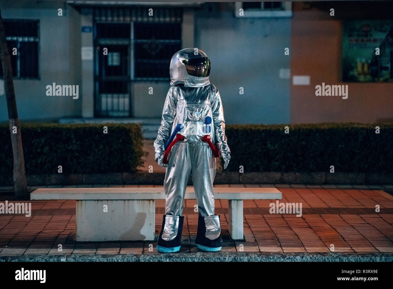 Spaceman standing at a bench in the city at night Stock Photo - Alamy